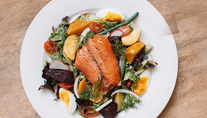 Grilled salmon on a mixed salad, perfect for restaurant or catering menus.